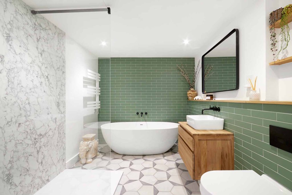 a full picture of a renovated bathroom with a green and white-marble aesthetic
